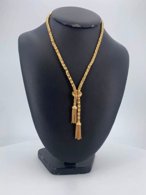 a gold chain necklace with a tassel on a mannequin