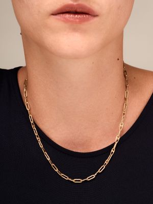 une femme portant un t-shirt noir et un collier à chaîne dorée