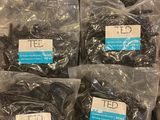 six packages of black chocolates in plastic bags on top of a wooden table