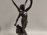 a bronze statue of a woman holding a bird on a pedestal