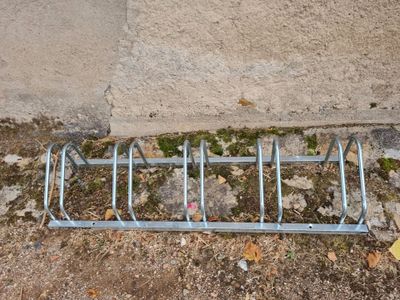 a metal bike rack on the ground next to a concrete wall