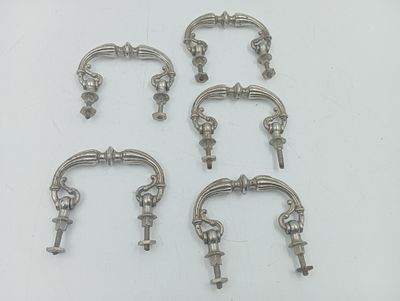 six raccords de tuyauterie en métal argenté posés sur une surface blanche