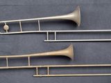 trois trombones en laiton sont alignés sur une surface noire