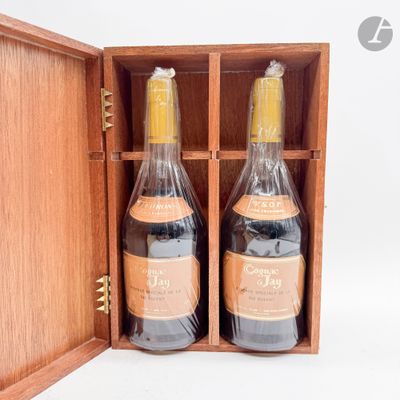 deux bouteilles de vin se trouvent dans une caisse en bois posée sur une surface blanche