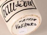 a white cup with black writing on it and a hand holding it
