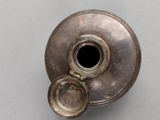a silver vase that has a small hole in it