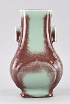 un vase vert et marron posé sur une surface blanche
