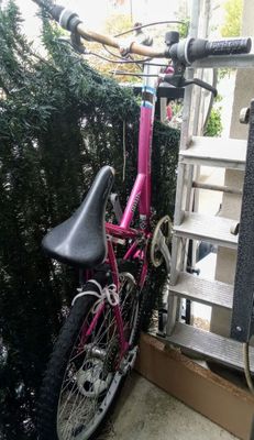 un vélo rose garé près d'une clôture