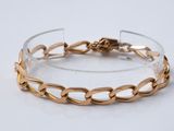gros plan d'un bracelet en or sur une surface blanche
