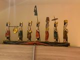 several figurines of people on a shelf with a clock in the background