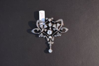 an antique diamond broochle on a black surface with a tag