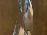 une sculpture en verre représentant un oiseau, posée sur une table en bois