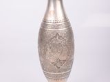 a silver vase that is sitting on a white surface