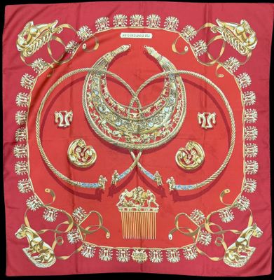 a red scarf with gold and silver jewelry on it