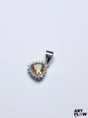 une image représentant un pendentif en forme de diamant jaune et blanc posé sur une surface blanche