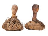 pair of carved wooden head sculptures on top of a piece of wood