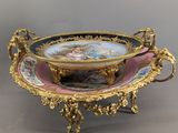 an ornately decorated bowl on a stand on a gray surface