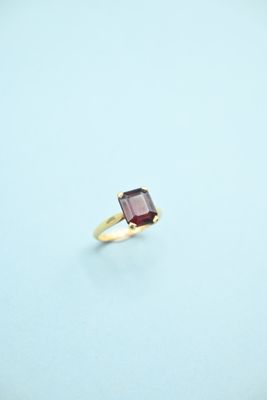 an image of a gold ring with a red stone on it