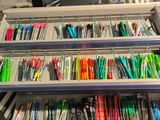 many pens and pencils on the shelves in the office