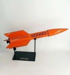 une maquette orange d'un avion de chasse posée sur un socle noir