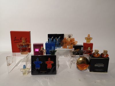 Plusieurs flacons de parfum différents sont alignés sur une surface blanche