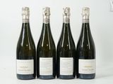 quatre bouteilles de vin sont alignées sur une surface blanche