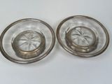 two clear glass plates with silver rims on a white surface