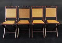 Suite de quatre chaises pliantes cannées en bois teinté.