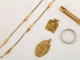 a gold necklace, ring, and other jewelry on a white surface