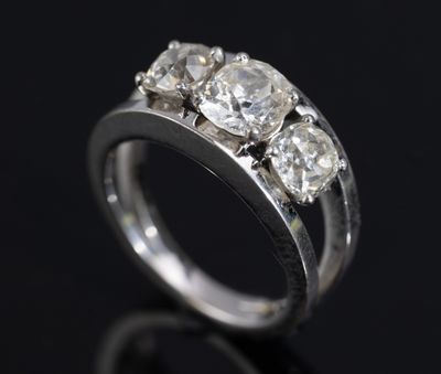 a close up of a three stone diamond ring on a black surface