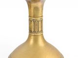 a gold vase that is sitting on a white surface