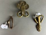 three pieces of metal are sitting on a table next to a pair of scissors and a pair of scissors