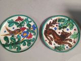 two plates with birds and flowers on them on a table