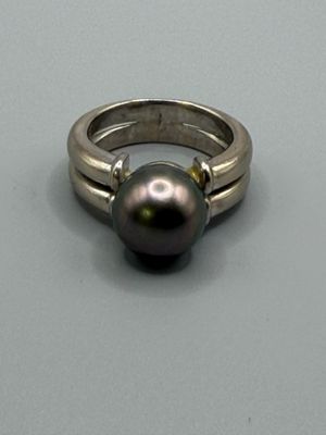 une bague ornée d'une perle noire, posée sur une table