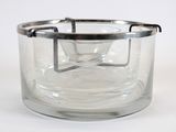 a glass container with a metal handle on a white surface