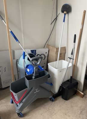 a mop, bucket, broom and bucket on the floor in a room