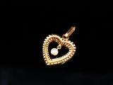 a gold heart pendant with a pearl in the middle