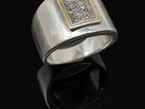 un gros plan d'une bague en argent et en or sur une surface noire