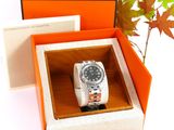 an orange box with a watch inside of it and a plant in the background