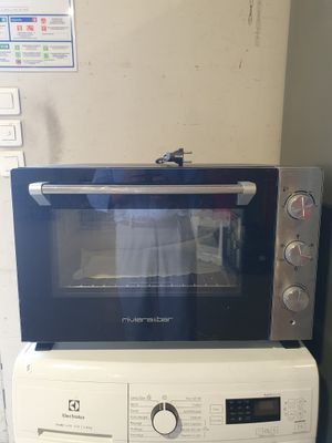un micro-ondes posé sur une machine à laver et un sèche-linge
