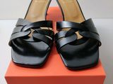 Les chaussures noires sont posées sur la boîte orange qui se trouve sur la table.