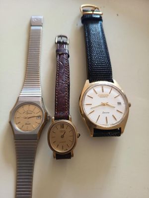 Trois montres différentes sont posées les unes à côté des autres sur une table.