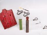 a red case with a knife, a book, and other items on a white surface