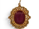 a gold pendant with a ruby stone surrounded by diamonds