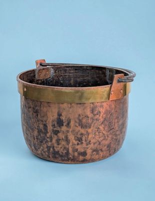 an old copper pot with a handle on a blue background