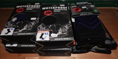 trois paires de chaussettes imperméables posées sur une table en bois