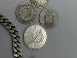 a lot of silver coins and a chain on a table