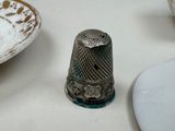 a thimble sitting on a table next to a plate
