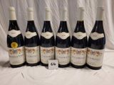 six bottles of red wine are lined up on a table