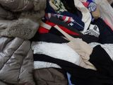 a pile of clothes on a bed with a teddy bear on top of it